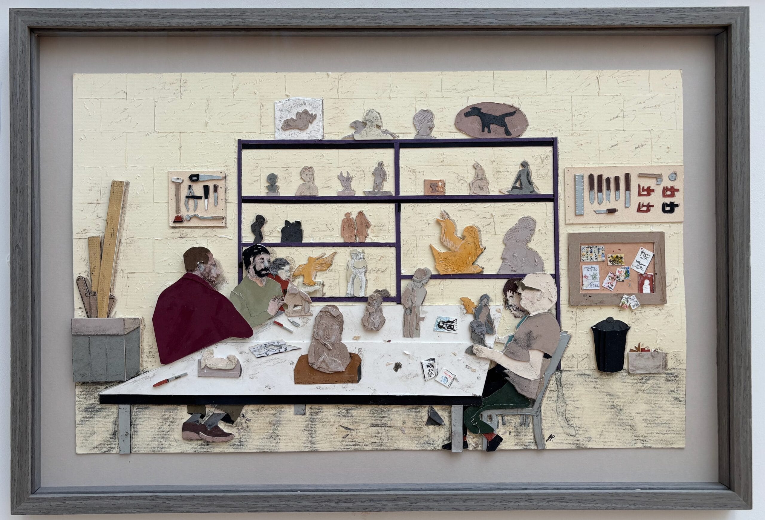 Framed mixed-media artwork depicting artists working at a studio table surrounded by sculptures and tools